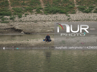 A man is fishing on the dried portion of the river Jhelum as the dry spell continues in Srinagar, Jammu and Kashmir, on July 23, 2024. A pro...