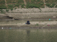 A man is fishing on the dried portion of the river Jhelum as the dry spell continues in Srinagar, Jammu and Kashmir, on July 23, 2024. A pro...