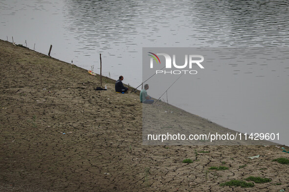 Men are fishing on the dried portion of the river Jhelum as the dry spell is continuing in Srinagar, Jammu and Kashmir, on July 23, 2024. A...