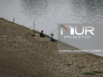 Men are fishing on the dried portion of the river Jhelum as the dry spell is continuing in Srinagar, Jammu and Kashmir, on July 23, 2024. A...