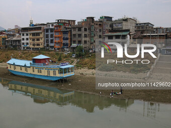 Men are fishing on the dried portion of the river Jhelum as the dry spell is continuing in Srinagar, Jammu and Kashmir, on July 23, 2024. A...