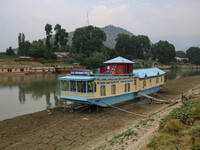 Owners are fixing wooden logs at the bottom to keep the balance of the houseboat on the dry beds of river Jhelum, as the dry spell is contin...