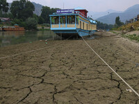 Owners are fixing wooden logs at the bottom to keep the balance of the houseboat on the dry beds of river Jhelum, as the dry spell is contin...