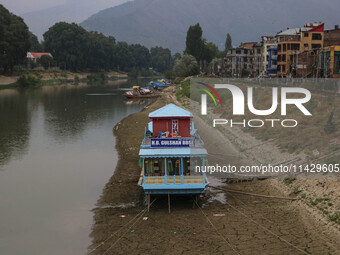 Owners are fixing wooden logs at the bottom to keep the balance of the houseboat on the dry beds of river Jhelum, as the dry spell is contin...