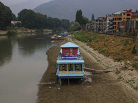 Owners are fixing wooden logs at the bottom to keep the balance of the houseboat on the dry beds of river Jhelum, as the dry spell is contin...