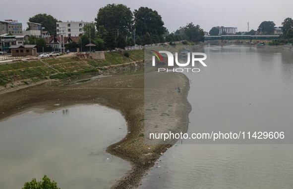 Men are fishing on the dried portion of the river Jhelum as the dry spell is continuing in Srinagar, Jammu and Kashmir, on July 23, 2024. A...