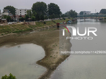 Men are fishing on the dried portion of the river Jhelum as the dry spell is continuing in Srinagar, Jammu and Kashmir, on July 23, 2024. A...