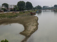 Men are fishing on the dried portion of the river Jhelum as the dry spell is continuing in Srinagar, Jammu and Kashmir, on July 23, 2024. A...