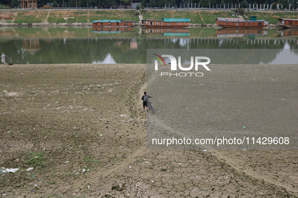 A man is walking along with his bicycle on the dried portion of the river Jhelum as the dry spell is continuing in Srinagar, Jammu and Kashm...