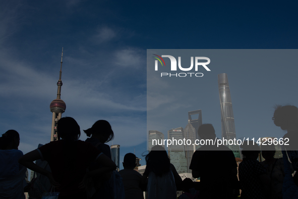 Tourists are staying in the shadow at the Bund in Shanghai, China, on July 23, 2024. 