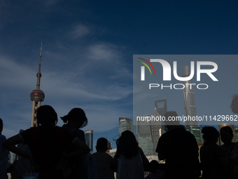 Tourists are staying in the shadow at the Bund in Shanghai, China, on July 23, 2024. (