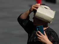 A woman is shielding herself with her handbag from the sun on Nanjing Road in Shanghai, China, on July 23, 2024. (