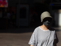 A woman is shielding herself with a mask from the sun on Nanjing Road in Shanghai, China, on July 23, 2024. (