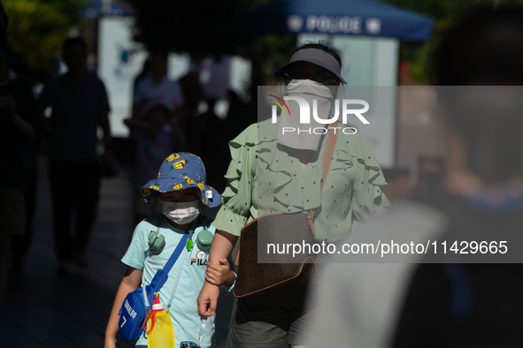 A woman is shielding herself with a mask from the sun on Nanjing Road in Shanghai, China, on July 23, 2024. 