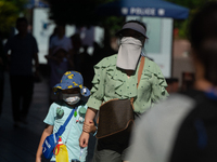 A woman is shielding herself with a mask from the sun on Nanjing Road in Shanghai, China, on July 23, 2024. (