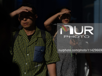 A man and woman are blocking the sun with their hands on Nanjing Road in Shanghai, China, on July 23, 2024. (