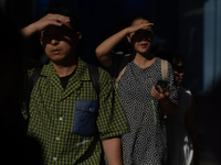 A man and woman are blocking the sun with their hands on Nanjing Road in Shanghai, China, on July 23, 2024. (