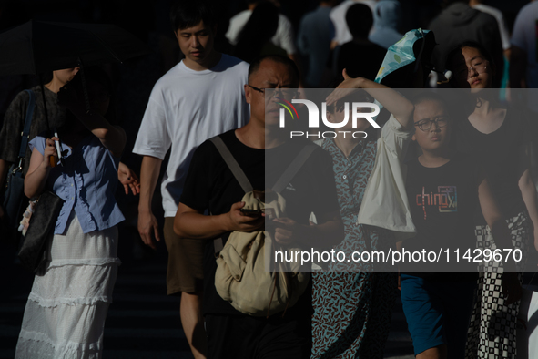 People are crossing the street on Nanjing Road in Shanghai, China, on July 23, 2024. 