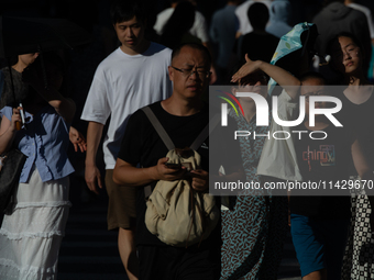 People are crossing the street on Nanjing Road in Shanghai, China, on July 23, 2024. (