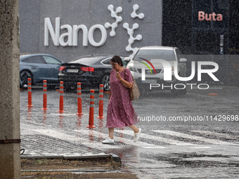 A woman is crossing a street in the rain in Odesa, Ukraine, on July 22, 2024. NO USE RUSSIA. NO USE BELARUS. (