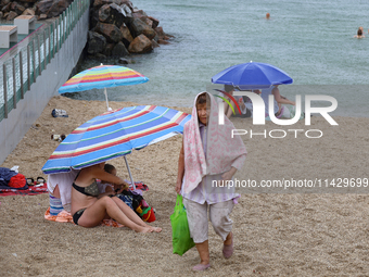 An elderly woman is leaving a beach covered with a towel as it rains in Odesa, Ukraine, on July 22, 2024. NO USE RUSSIA. NO USE BELARUS. (