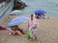 An elderly woman is leaving a beach covered with a towel as it rains in Odesa, Ukraine, on July 22, 2024. NO USE RUSSIA. NO USE BELARUS. (