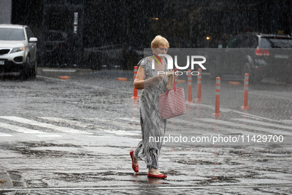 A woman is walking along a street in the rain in Odesa, Ukraine, on July 22, 2024. NO USE RUSSIA. NO USE BELARUS. 