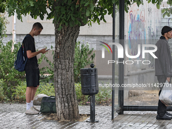 Two men are standing in the street in the rain in Odesa, Ukraine, on July 22, 2024. (