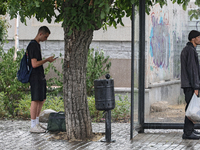 Two men are standing in the street in the rain in Odesa, Ukraine, on July 22, 2024. (