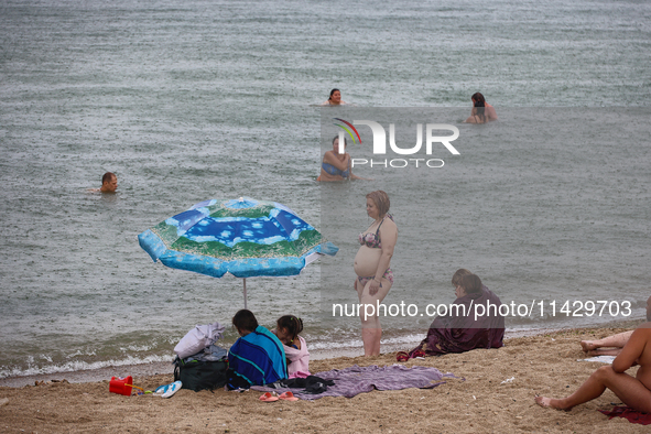 People are staying on a beach as it is raining in Odesa, Ukraine, on July 22, 2024. NO USE RUSSIA. NO USE BELARUS. 