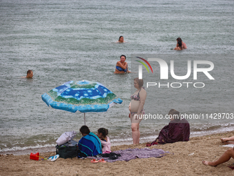 People are staying on a beach as it is raining in Odesa, Ukraine, on July 22, 2024. NO USE RUSSIA. NO USE BELARUS. (