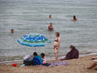 People are staying on a beach as it is raining in Odesa, Ukraine, on July 22, 2024. NO USE RUSSIA. NO USE BELARUS. (