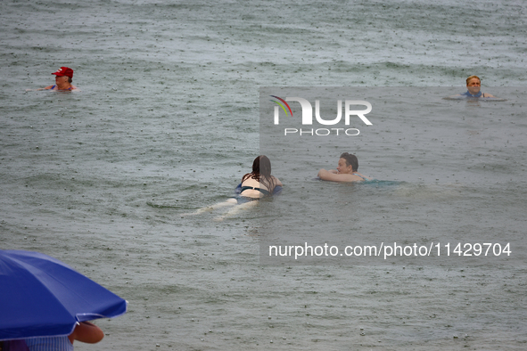 People are bathing in the Black Sea during the rain in Odesa, Ukraine, on July 22, 2024. 