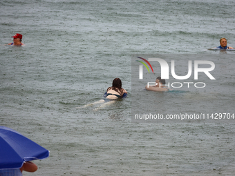 People are bathing in the Black Sea during the rain in Odesa, Ukraine, on July 22, 2024. (