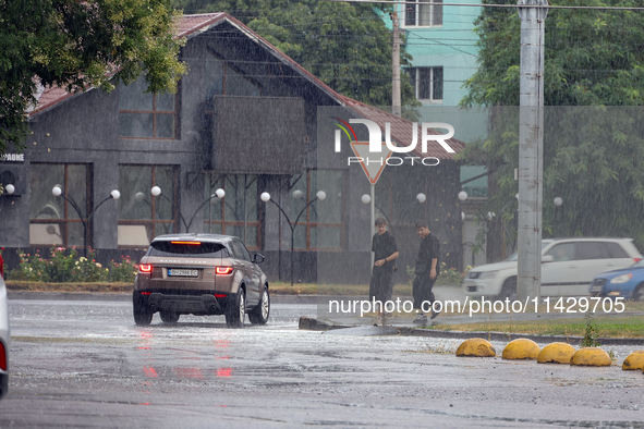 Two boys are walking along the street in the rain in Odesa, Ukraine, on July 22, 2024. NO USE RUSSIA. NO USE BELARUS. 