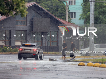 Two boys are walking along the street in the rain in Odesa, Ukraine, on July 22, 2024. NO USE RUSSIA. NO USE BELARUS. (