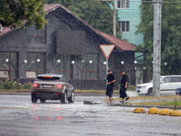 Two boys are walking along the street in the rain in Odesa, Ukraine, on July 22, 2024. NO USE RUSSIA. NO USE BELARUS. (