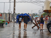 Two boys are walking under the blanket as it is raining in Odesa, Ukraine, on July 22, 2024. (