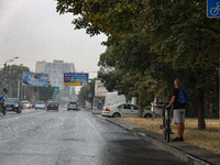 A man is holding a bicycle and standing on the roadside in the rain in Odesa, Ukraine, on July 22, 2024. NO USE RUSSIA. NO USE BELARUS. (