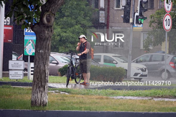 A woman is holding a bicycle in the rain in Odesa, Ukraine, on July 22, 2024. NO USE RUSSIA. NO USE BELARUS. 