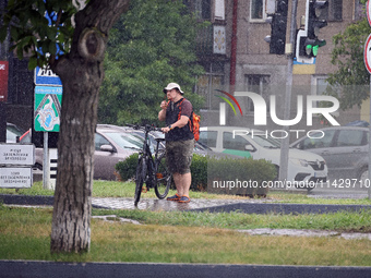 A woman is holding a bicycle in the rain in Odesa, Ukraine, on July 22, 2024. NO USE RUSSIA. NO USE BELARUS. (