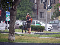 A woman is holding a bicycle in the rain in Odesa, Ukraine, on July 22, 2024. NO USE RUSSIA. NO USE BELARUS. (