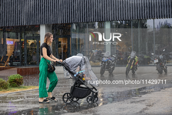 A woman is pushing a buggy in the rain in Odesa, Ukraine, on July 22, 2024. 