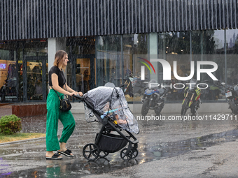 A woman is pushing a buggy in the rain in Odesa, Ukraine, on July 22, 2024. (