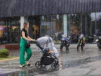 A woman is pushing a buggy in the rain in Odesa, Ukraine, on July 22, 2024. (