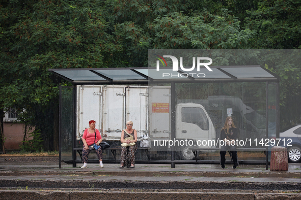 Women are staying at a public transport stop during the rain in Odesa, Ukraine, on July 22, 2024. NO USE RUSSIA. NO USE BELARUS. 