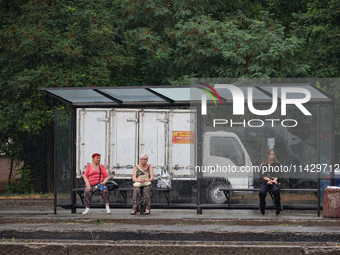 Women are staying at a public transport stop during the rain in Odesa, Ukraine, on July 22, 2024. NO USE RUSSIA. NO USE BELARUS. (