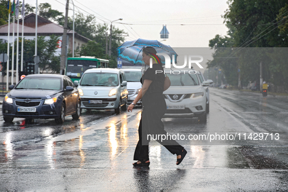 A woman is crossing a street in the rain with an umbrella in Odesa, Ukraine, on July 22, 2024. NO USE RUSSIA. NO USE BELARUS. 