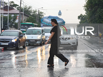 A woman is crossing a street in the rain with an umbrella in Odesa, Ukraine, on July 22, 2024. NO USE RUSSIA. NO USE BELARUS. (