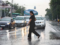 A woman is crossing a street in the rain with an umbrella in Odesa, Ukraine, on July 22, 2024. NO USE RUSSIA. NO USE BELARUS. (